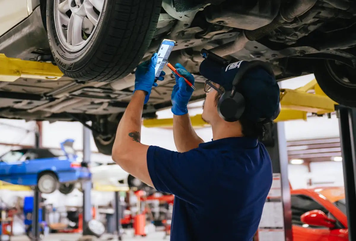 Technician inspecting the underside of a vehicle on a lift
