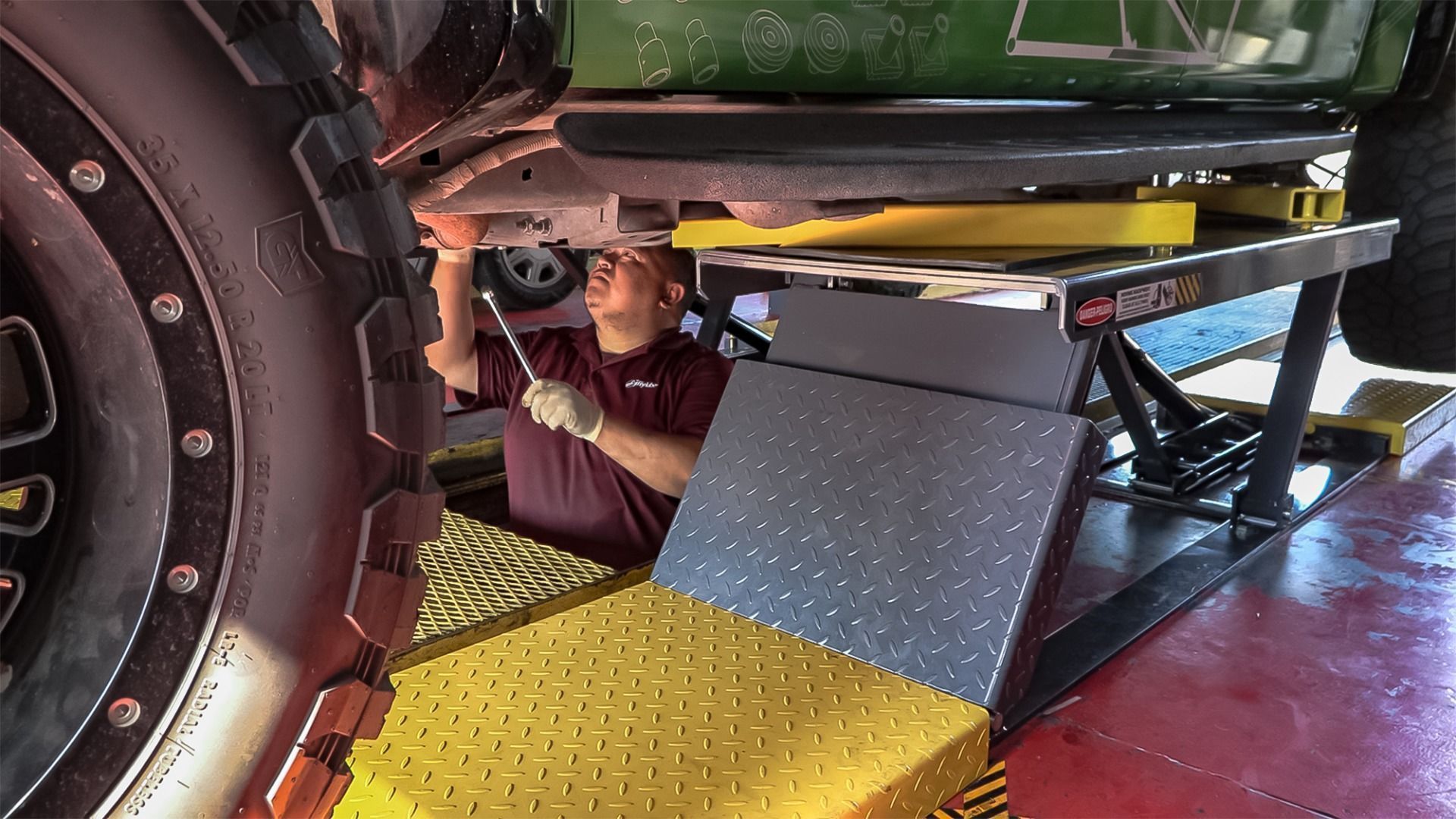 BendPak P-9000LT low-rise pit lift, technician servicing vehicle undercarriage