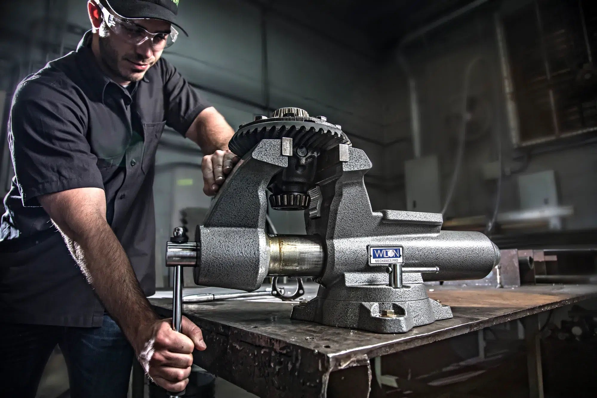 Technician working metal in a heavy bench vise in a fabrication shop