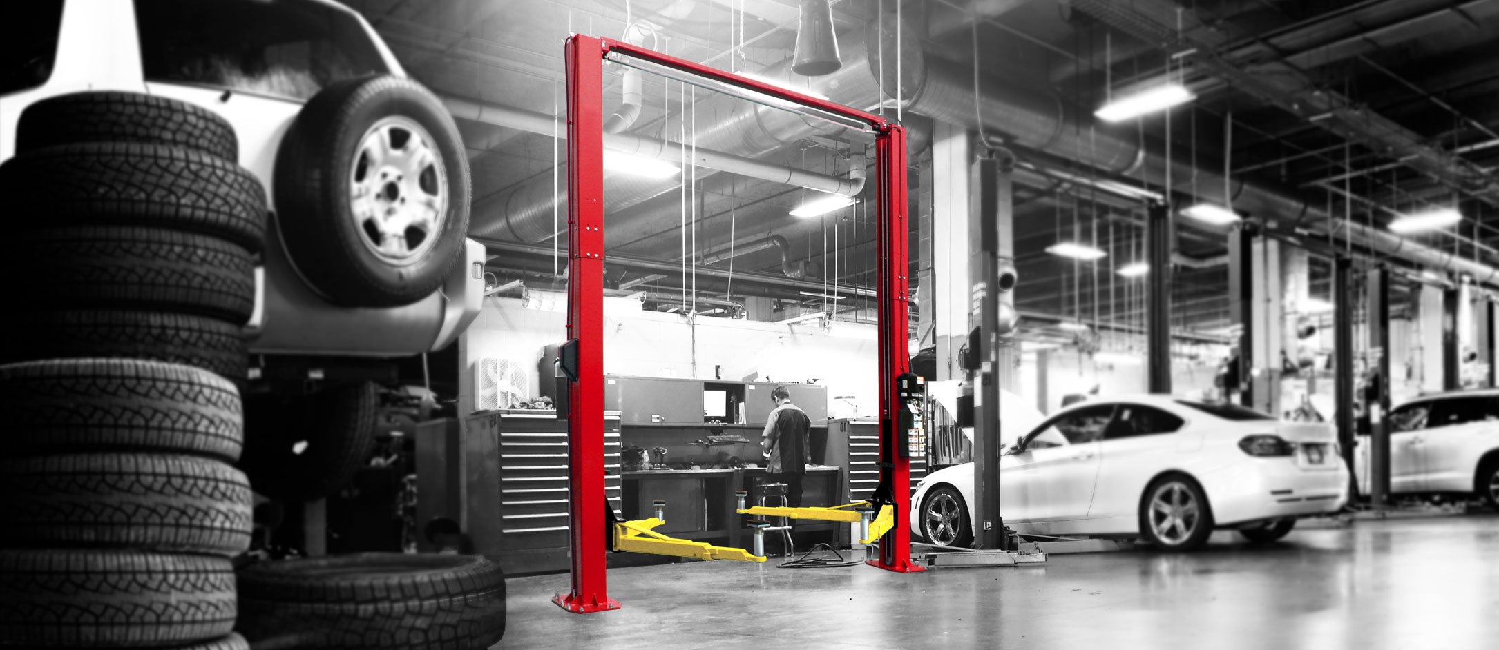 Two-post lift raising a vehicle in a professional auto shop
